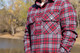 Man wearing flannel shirt on beach, next to water.